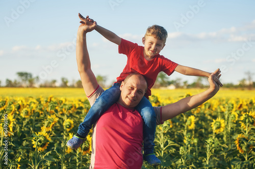 father with child in a field of blooming sunflowers , father's day