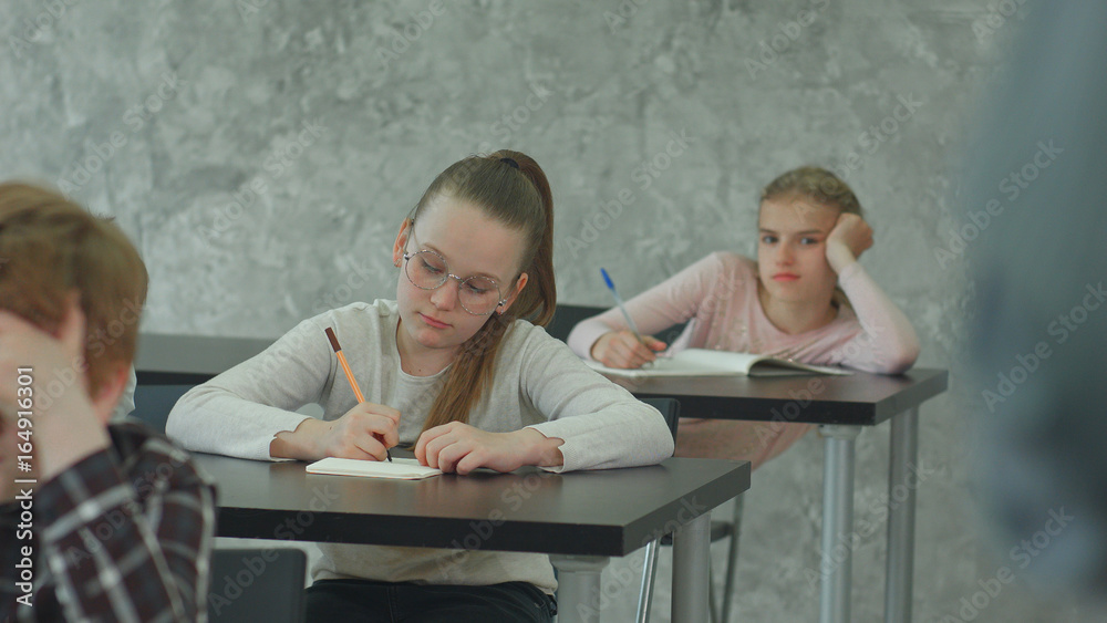 Students in school uniform taking exam at desk in a classroom Students in school uniform taking exam at desk in a classroom
