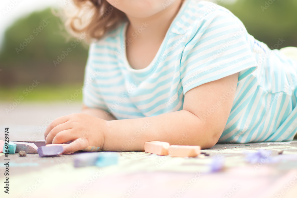 Closeup photo, toddler girl drawing with piece of color chalk Closeup photo, toddler girl drawing with piece of color chalk