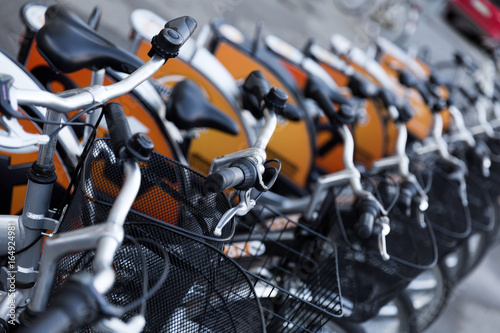 A rental bicycles stand in a row on a parking.