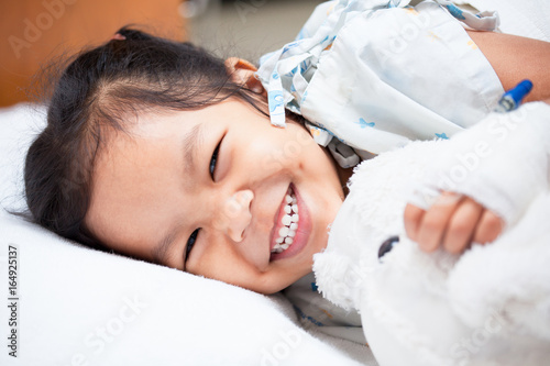 Obraz na płótnie Sick asian child girl is lay down on the bed and smiling when she feel better in