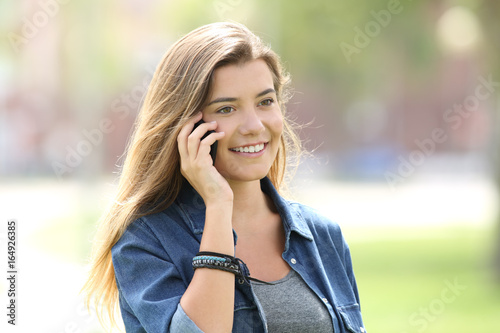 Teen girl calling on phone outdoors in a park