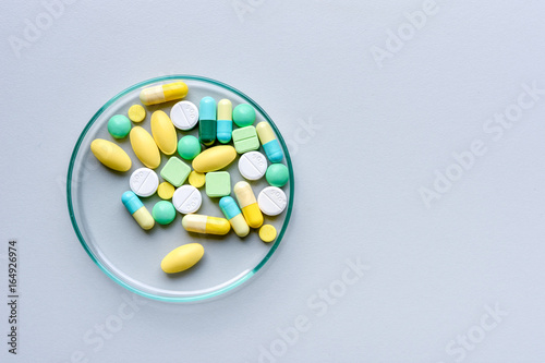 .Colorful medicines in tablets and capsules are placed in a clear glass plate placed on the table.