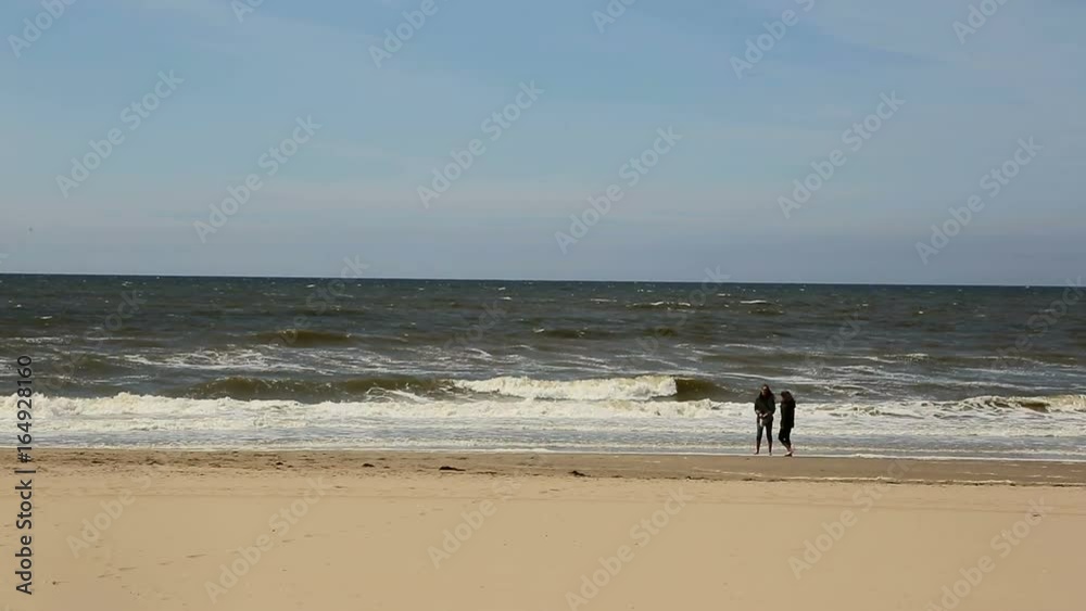 Two young women walking away along a beach Two young women walking away along a beach