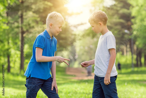 Two boys play rock paper scissors in the park