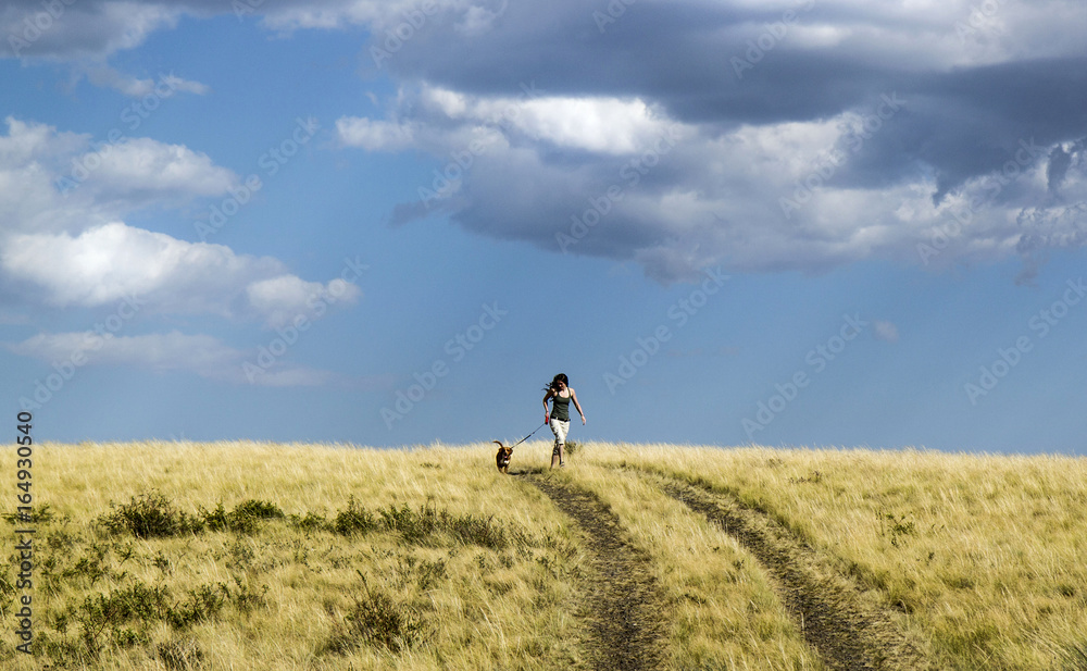Girl running with a dog on country road in summer nature.