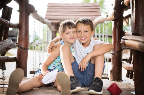 Two small kids sitting and hugging outdoors. photo