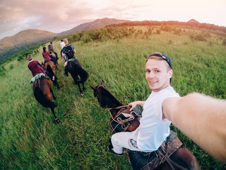 male rider on horseback holds a camera in his hand and takes a picture of Selfie.
