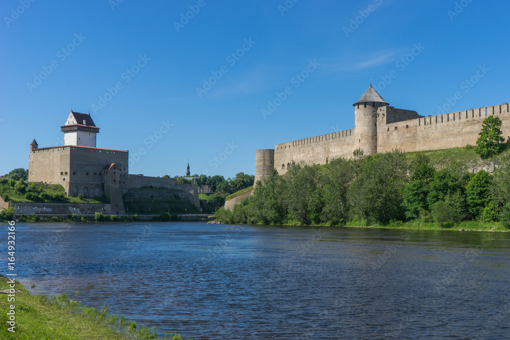 Narva Herman castle and Ivangorod fortress stand opposite to each other on banks of Narva river. Medieval fortifications on Estonian-Russian state border. National historical travel attraction