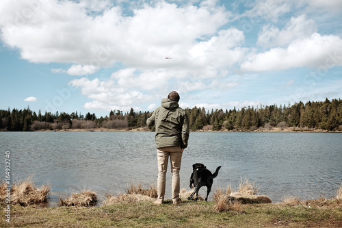 Homme jouant avec son chien au bord d'un lac en Auvergne