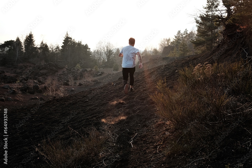 Homme qui court sur un volcan au coucher de soleil