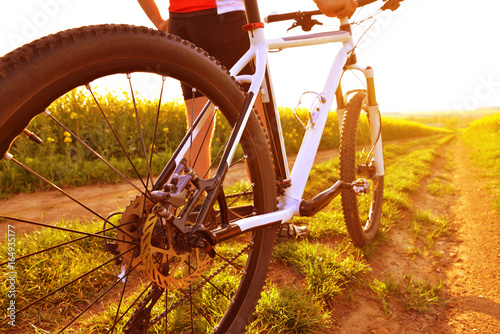 Cyclist with mountain bike on dirt road at sunset. Healthy lifestyle concept.