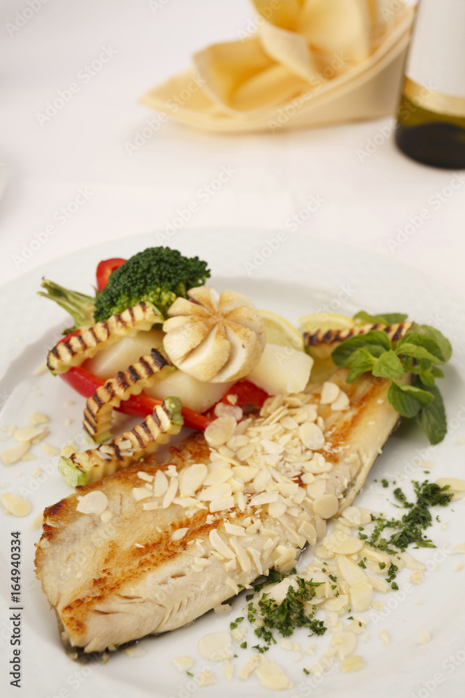 Hake fillet with grilled vegetables arranged on a plate, Traditional dish in elegant setting, Selective focus with soft light Hake fillet with grilled vegetables arranged on a plate, Traditional dish in elegant setting, Selective focus with soft light