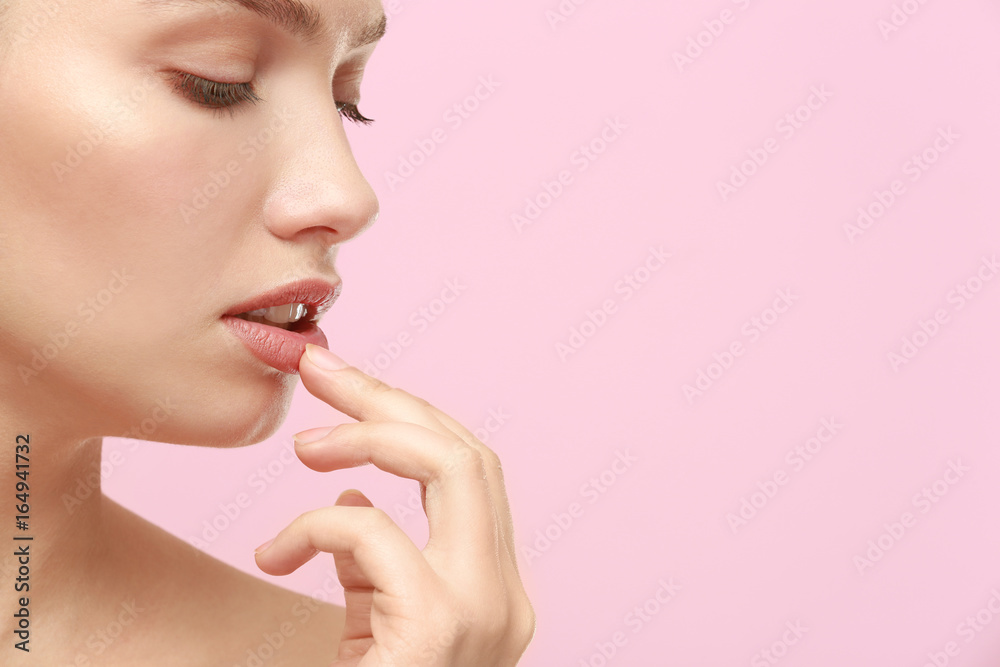 Closeup view of beautiful young woman with natural makeup touching lips on color background Closeup view of beautiful young woman with natural makeup touching lips on color background
