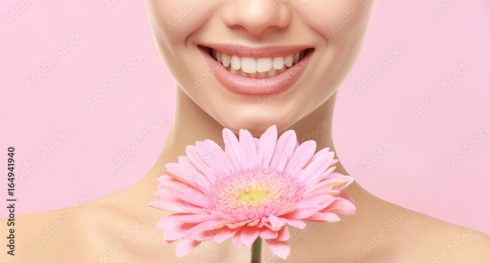 Closeup view of beautiful young woman with natural lips makeup and flower on color background