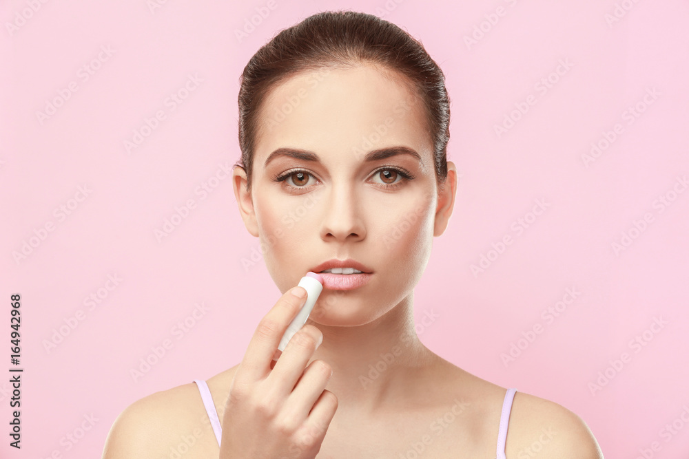 Closeup view of beautiful young woman applying lipstick, color background Closeup view of beautiful young woman applying lipstick, color background