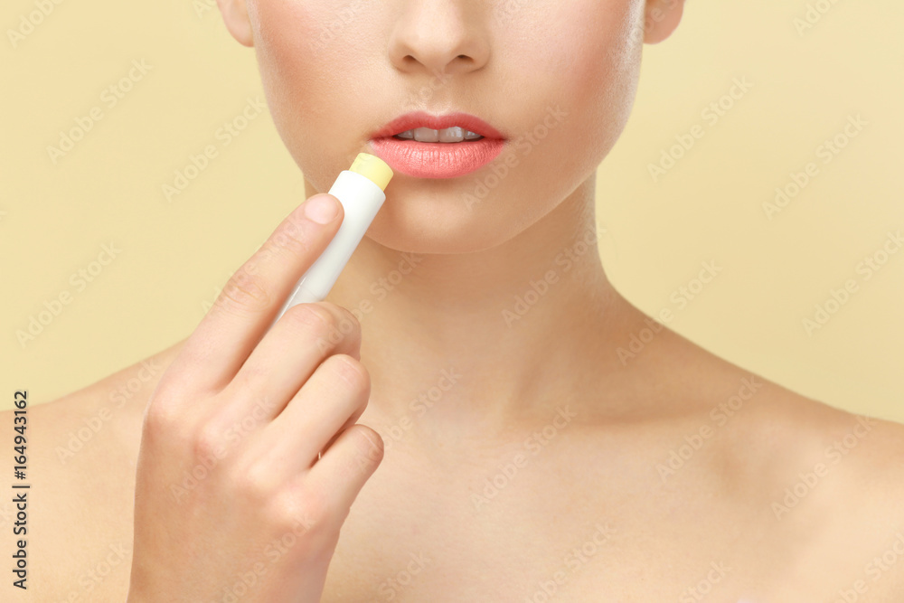 Closeup view of beautiful young woman applying lipstick, color background Closeup view of beautiful young woman applying lipstick, color background