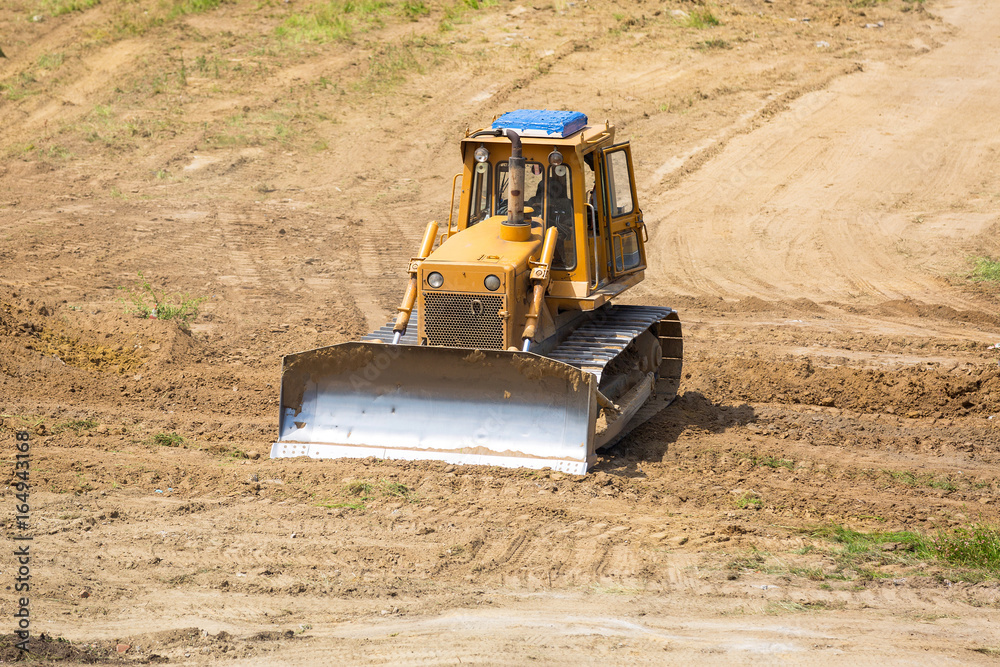 Yellow bulldozer with caterpillar moving ground with scoop Yellow bulldozer with caterpillar moving ground with scoop