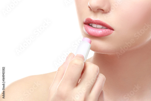Closeup view of beautiful young woman applying lipstick  white background