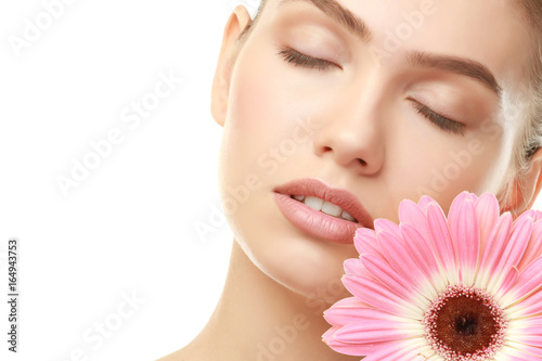 Closeup view of beautiful young woman with natural lips makeup and flower on white background