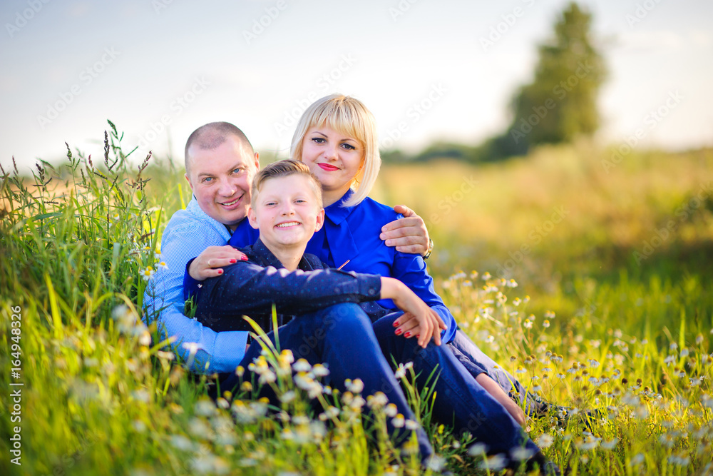 Fototapeta premium Happy family in the evening in the field among wild flowers, embrace and smile
