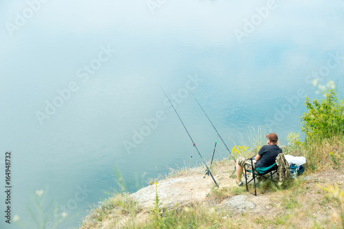 Fisherman relaxing near the river and trying to catch fish with two fishing rods. Peaceful water background