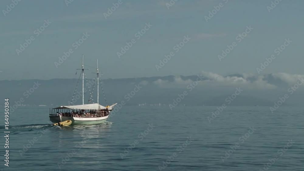 Tour boat with tourists sailing away from Ilhabela, Brazil Tour boat with tourists sailing away from Ilhabela, Brazil