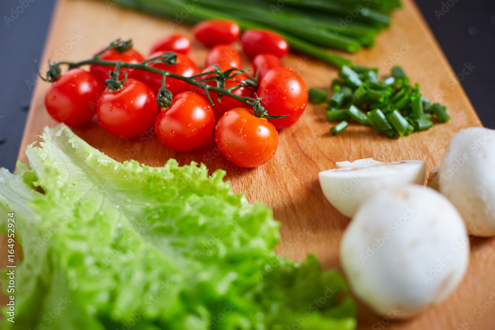 Fresh and tasty tomatoes, salad, onion, champignon on wooden cutting board