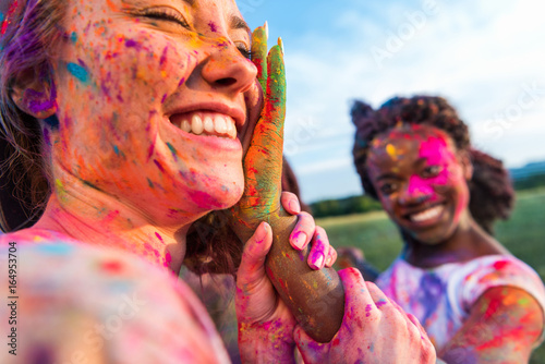Fototapeta Naklejka Na Ścianę i Meble -  happy young multiethnic friends having fun with colorful powder at holi festival of colors