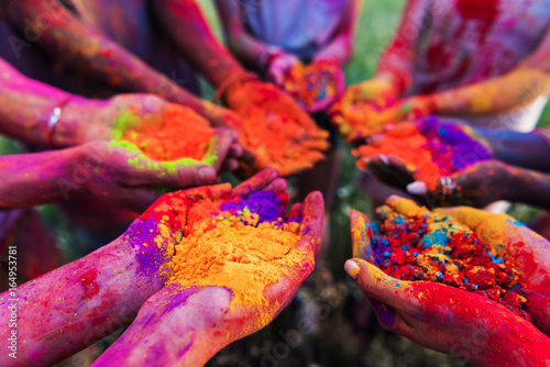 close-up partial view of young people holding colorful powder in hands at holi festival photo