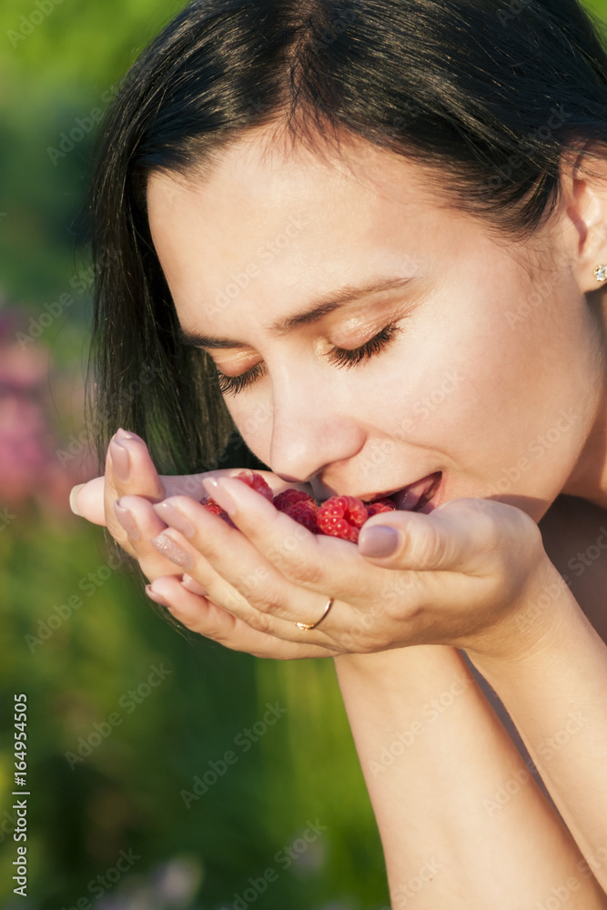 Happy beautiful girl eating raspberries, holding berries in the palm of her hand Happy beautiful girl eating raspberries, holding berries in the palm of her hand