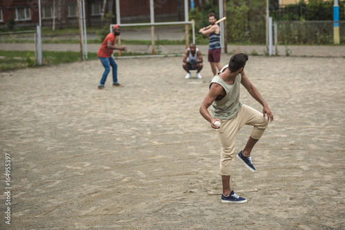 group of young multiethnic men playing baseball on court