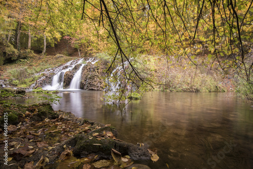 Waterfall in the forest during autumn. Beautiful view of a river with an waterfall in the forest photo