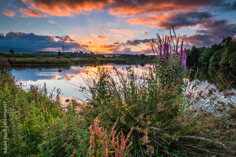 Obraz premium Sunset at Branton Lakes / Branton Lakes Nature Reserve was constructed from a former mineral quarry, located at Branton in the Breamish Valley, Northumberland