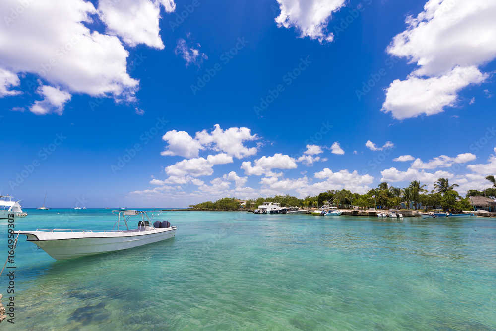 White boat near the rocky shore in Bayahibe, La Altagracia, Dominican Republic. Copy space for text. White boat near the rocky shore in Bayahibe, La Altagracia, Dominican Republic. Copy space for text.
