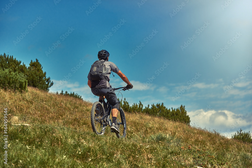 Fototapeta premium Mountain biking man riding on bike in summer mountains forest landscape.MTB mountain biker enjoys the view