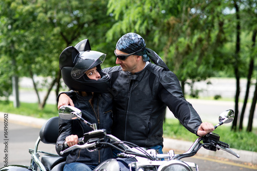 A beautiful couple in love is riding a motorbike.
