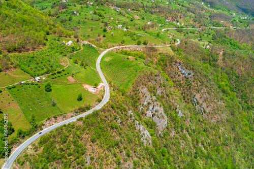 Top view of the winding highway and farm gardens