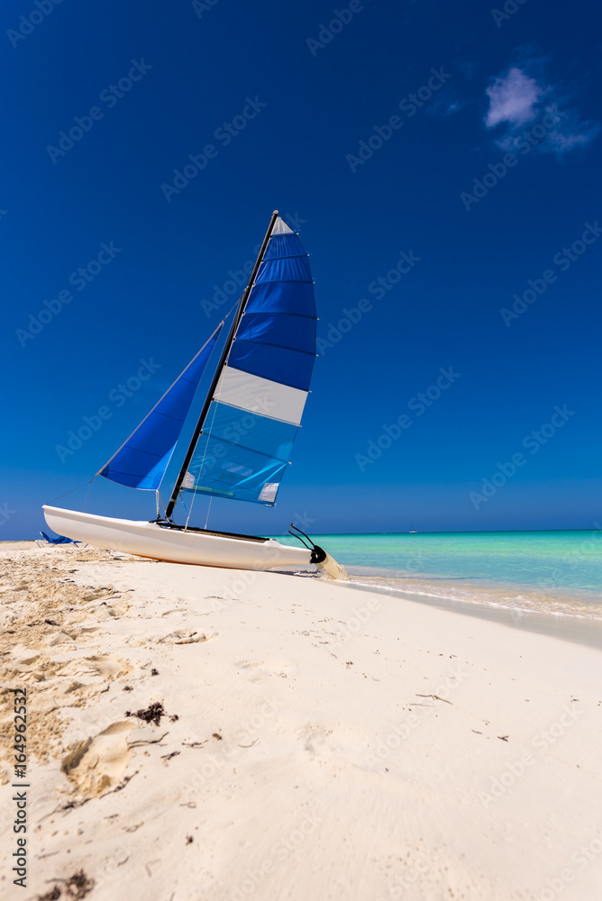 Fototapeta premium Sailboat on the sandy beach of the Playa Paradise of the island of Cayo Largo, Cuba. Copy space for text. Vertical.