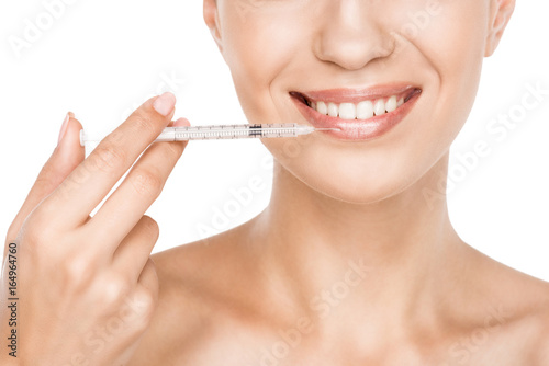 cropped view of beautiful smiling woman making beauty injection for lips, isolated on white