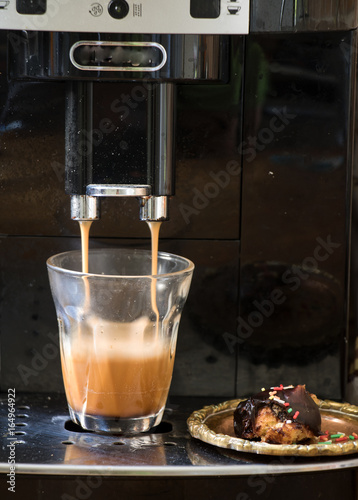 Espressomaschine beim Kaffee-Durchlauf mit einem Schokokeks  photo