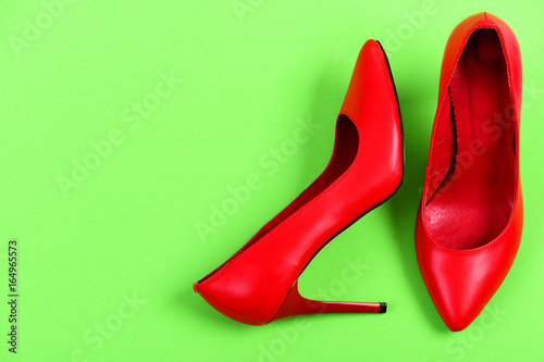 Red high heel shoes isolated on green background, top view