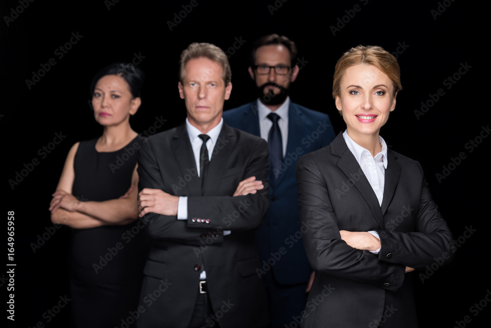 confident multiethnic group of businesspeople standing with crossed arms and looking at camera isolated on black confident multiethnic group of businesspeople standing with crossed arms and looking at camera isolated on black
