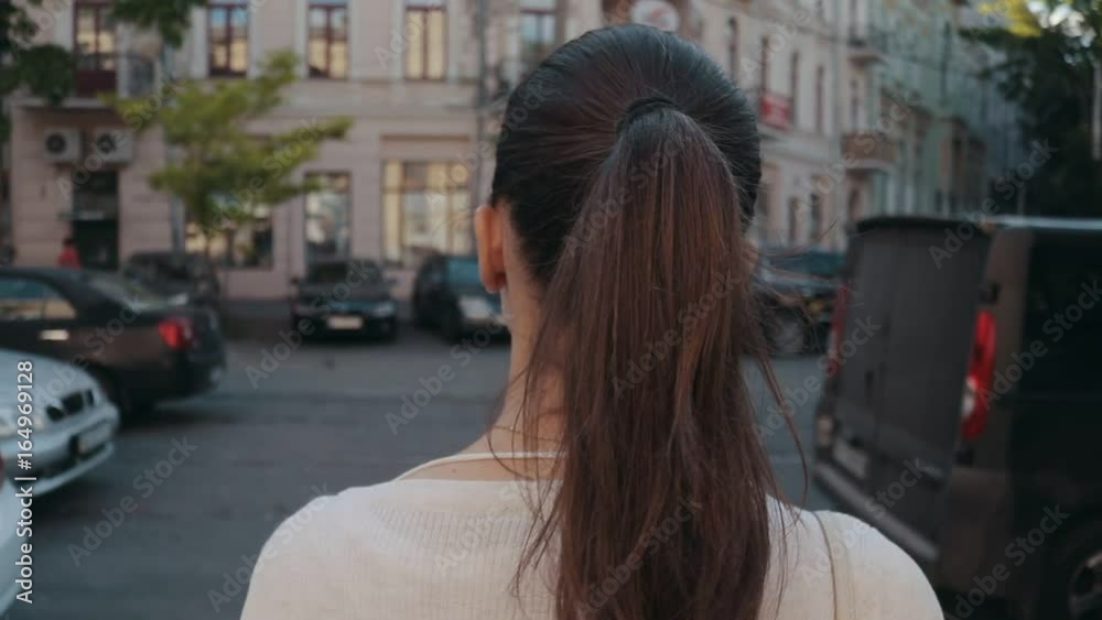 Brunette woman stands at a pedestrian crossing in the city in summer, slow motion Brunette woman stands at a pedestrian crossing in the city in summer, slow motion