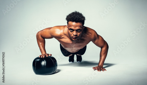 Young fit man doing push up on medicine ball