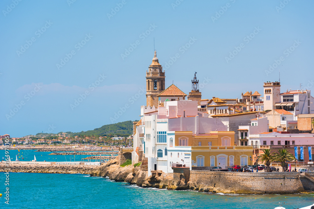 View of the historical center and the ñhurch of Sant Bartomeu and Santa Tecla in Sitges, Barcelona, Catalunya, Spain. Copy space for text. Isolated on blue background.