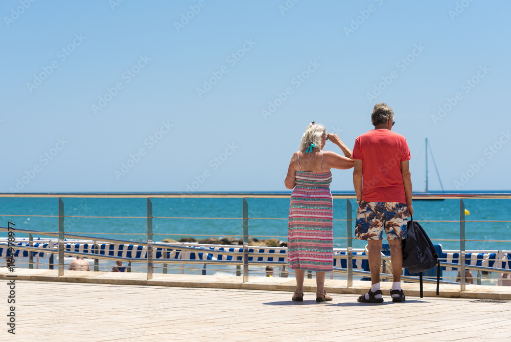 Mature married couple on the waterfront in the Sitges, Barcelona, Catalunya, Spain. Copy space for text.