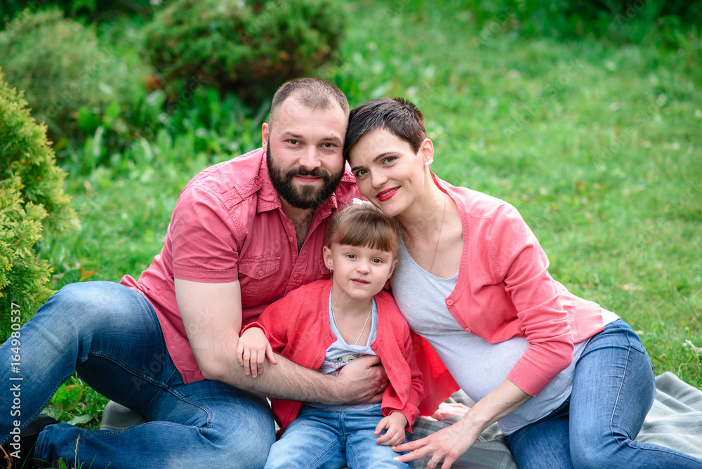 Happy family walking in the park. Pregnancy.