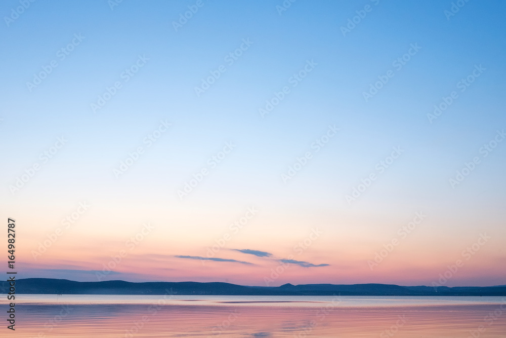 soft and calm sunset at Balaton lake in summer - thin clouds, velvet sky and hills in background