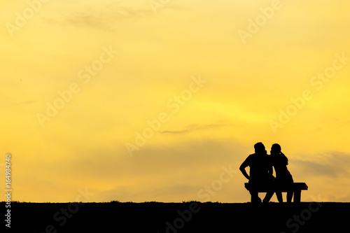 Back view of a couple silhouette sitting on Chair at colorful sunset on background © thechatat